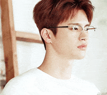 a close up of a person wearing glasses and a white shirt with the word ed on it