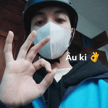 a man wearing a helmet and a face mask shows a ok sign