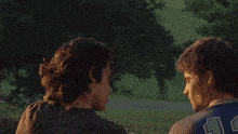 a man in a blue shirt kisses another man in front of an explosion