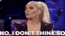 a woman is sitting in front of a blue background and says `` no , i don 't think so ''