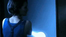 a woman in a blue tank top is standing in the dark