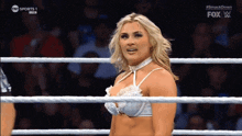 a woman in a white bra stands in a wrestling ring with a fox logo on the bottom