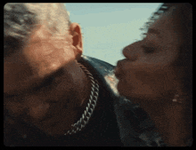 a close up of a woman kissing a man 's neck