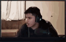 a young man wearing headphones is sitting in front of a computer .