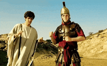 a man dressed as a roman soldier stands next to another man dressed as a toga