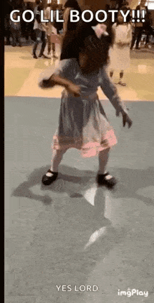 a little girl in a dress is dancing on a dance floor in a gym .