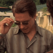 a man wearing sunglasses and a striped shirt looks down