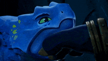 a close up of a blue toy with a green eye and teeth