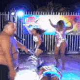 a group of people are dancing on a stage in front of a pool .
