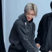 a man in a black hoodie is standing next to a man in a black jacket .