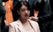 a woman in a pink suit is sitting in a crowd of people