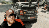 a man wearing headphones stands in front of a car that says www.skoda-auto.com on the back