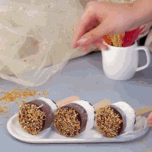 a white plate topped with three chocolate covered marshmallows on sticks