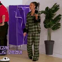 a woman in plaid pajamas stands in front of a purple cabinet