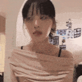a woman in a white off the shoulder top looks at the camera