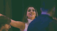 a woman in a white turtleneck is dancing with her arms outstretched in a dark room .