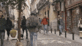 people walking down a street in front of a store that says milko