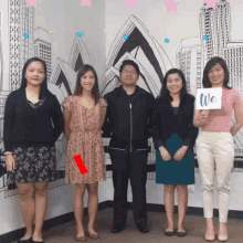 a group of people standing in front of a wall with a drawing of the opera house and a sign that says we