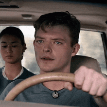 a man wearing a necklace is driving a car
