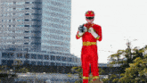 a man in a red power ranger costume holds a cell phone