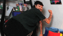 a man with tattoos on his arms is standing in front of a wall