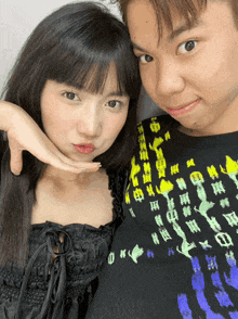 a boy and a girl are posing for a picture and the girl is wearing a black shirt with chinese writing
