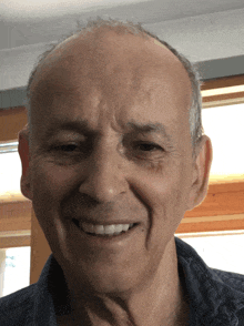 a man with a bald head is smiling and wearing a black shirt