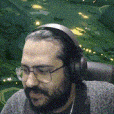 a man with a beard wearing headphones and glasses is sitting in a chair .