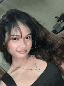 a woman wearing a black top and a necklace with a heart pendant