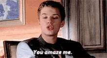 a young man is sitting in a chair and saying `` you amaze me . ''