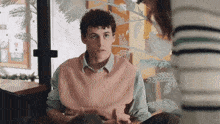 a man wearing a pink vest is talking to a woman