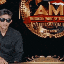 a man wearing sunglasses stands in front of a sign that says am