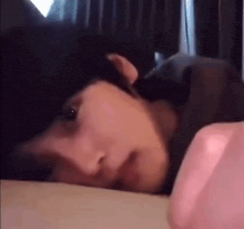 a close up of a person laying on a bed looking at their phone .