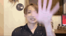 a young man in a black shirt is waving his hand