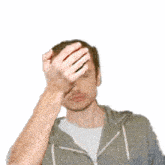a man is holding his hand to his forehead while wearing a hoodie .
