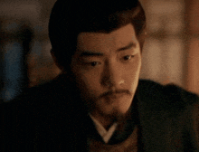 a man with a beard is wearing a kimono and looking at the camera