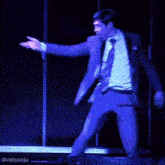 a man in a suit and tie is dancing on a stage with divahyunju in the corner