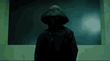 a person wearing a black hoodie is standing in front of a green wall .