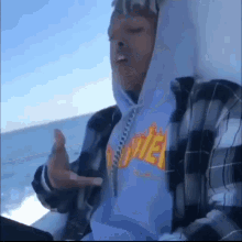 a man wearing a plaid shirt and a hoodie with the word thrasher on it