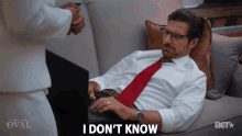 a man laying on a couch using a laptop with the words " i don 't know " next to him