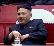 a man in a suit is sitting at a table with a glass of water and smiling .