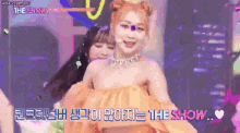 a woman in an orange dress is dancing on a stage in front of a group of people .