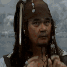 a man with dreadlocks and a beard is dressed as jack sparrow from pirates of the caribbean