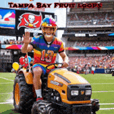 a man wearing a rainbow jersey with the number 13 is riding a tractor on a football field