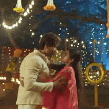 a man and a woman are kissing in a room with a lot of lights .