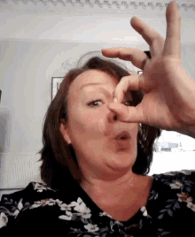 a woman in a floral shirt is making a face with her hands