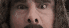 a close up of a man 's face with a mustache and a surprised look on his face .