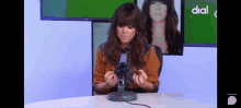 a woman sitting in front of a microphone with the word dial on the bottom left
