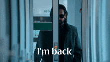 a man standing in a doorway with the words " i 'm back " on the bottom