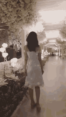 a woman in a blue dress is walking down a hallway decorated with flowers .
